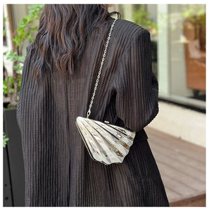 Close-up of a silver shell-shaped metallic crossbody bag with a slim metal chain strap