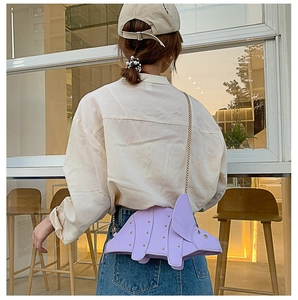 Detail of lavender cartoon dinosaur bag with gold rivets and fine metal chain strap