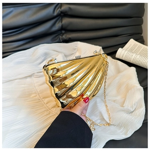Detailed view of a gold shell-shaped clutch bag with sleek metallic ribs and chain strap