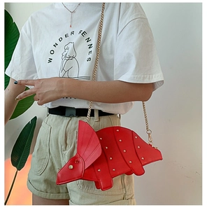 Detail of red triceratops handbag featuring gold studs and elegant metal chain strap