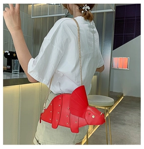 Red triceratops dinosaur shoulder bag with silver rivets and gold chain on a model