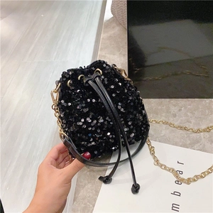 Glossy black sequin bucket bag with gold chain strap and drawstring closure for parties