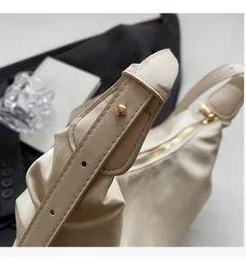 Detail of adjustable gold buckle and zipper on beige leather shoulder bag for women
