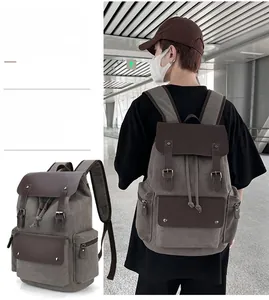 Detail of grey canvas backpack with brown leather trim and drawstring closure mechanism