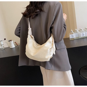 Detailed view of cream hobo bag with soft leather pleats worn over a blazer