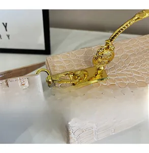 Close-up of beige crocodile pattern bag with vintage gold metal handle and engraved medal