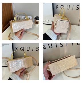 Detail of cream crocodile embossed handbag with golden metal circular handle and shoulder strap