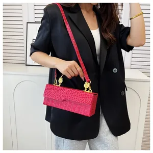 Detail of red crocodile texture evening bag with metallic ring handle and shoulder strap