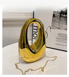Detail of a golden mirror-finish oval evening bag with a sleek metal chain strap