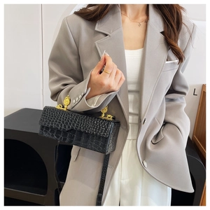 Detail of black crocodile pattern crossbody bag with golden vintage metal buckle closure