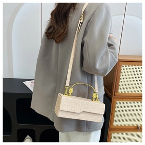 Detail view of beige crocodile pattern bag with golden lion head relief handle
