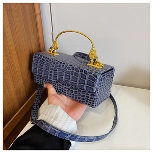 Detail of navy blue crocodile pattern handbag with gold handle and vintage relief