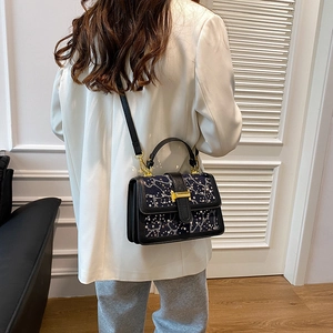 Modern sparkly crossbody bag with golden H-buckle shown on a white blazer outfit