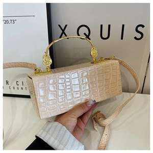 Detailed view of cream crocodile texture evening bag with vintage gold relief handle