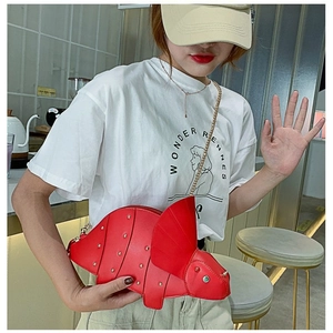 Chic red triceratops dinosaur shoulder bag with gold studs and chain strap worn by a model