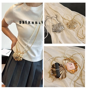 Macro detail of shell-shaped mini bag with pearl chain strap and metallic finish
