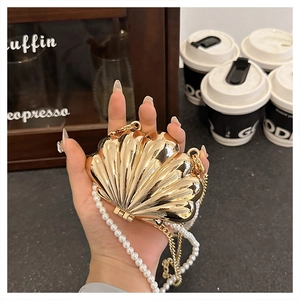 Detailed view of a golden shell evening bag with pearl strap and mirror finish
