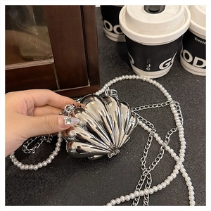 Detail of silver shell-shaped evening clutch bag with pearl and metal chain strap