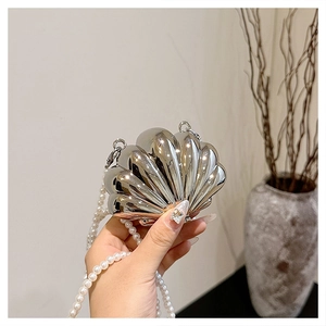 Close-up of silver shell-shaped evening bag with pearl chain strap and metallic finish