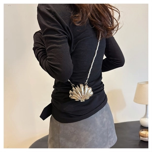 Detail of mirror gold shell crossbody bag with decorative pearl chain strap