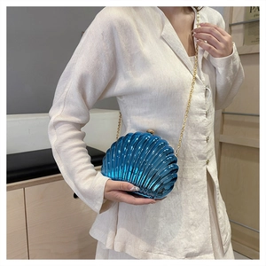 Detailed view of glossy blue shell-shaped clutch bag with golden metal chain strap