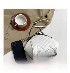 Detail of white quilted leather texture and vintage metal ball clasp on small clutch bag