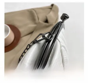 Close-up of sleek black metallic hardware and chain strap on a white leather handbag