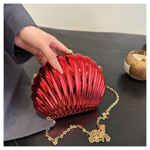 Detail view of a glossy red shell-shaped clutch bag with golden chain and ball clasp