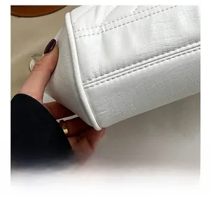 Detail showing precise stitching and premium leather texture on white shell bag