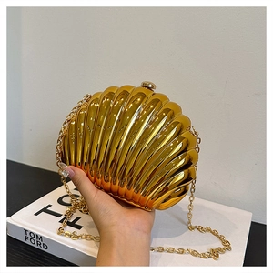 Detailed view of a gold shell-shaped clutch bag with textured metallic finish and chain