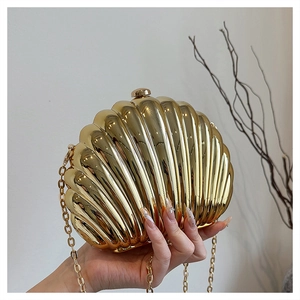 Detailed close-up of a golden shell-shaped metal clutch bag with radial texture and chain