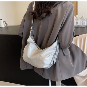 Elegant silver hobo shoulder bag with textured metallic finish on a model