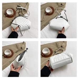 Detailed view of white quilted crossbody bag with metal kiss-lock and chain strap