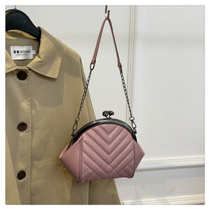 Detail of pink quilted handbag featuring black metal clasp and chain shoulder strap