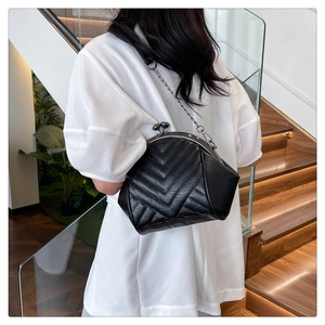 Close-up of black V-quilted faux leather bag with metal clasp and silver chain strap
