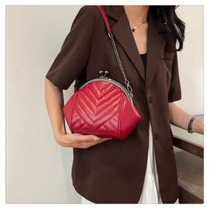 Close-up of red V-quilted frame bag with silver chain strap worn with a blazer