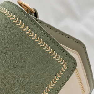 Detail shot of the elegant cream stitching on dark green textured leather bag