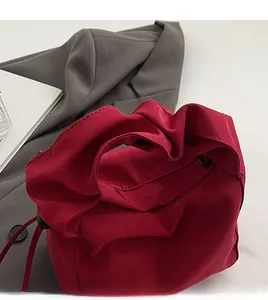 Close-up of deep red bag featuring a stylish pleated handle and durable fabric texture