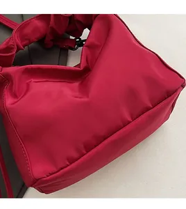 Detail of burgundy ruched shoulder bag with cloud-style strap and glossy nylon fabric