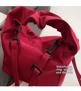 Close-up of detachable metal hook and ruffle handle on dark red shoulder bag