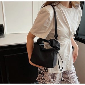 Detail of a black crossbody bag showing knotted handle texture and nylon canvas finish