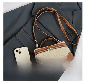 Detailed size comparison of beige canvas and brown leather crossbody bag with a smartphone