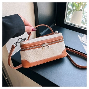 Detail of canvas handbag with brown leather trim and silver metal zipper hardware