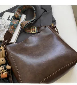 Detail of dark brown bucket bag with woven ethnic shoulder strap and rabbit charm