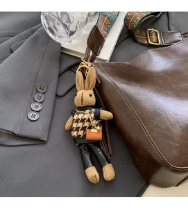 Detail of a brown knit rabbit bag charm with houndstooth sweater and leather pants