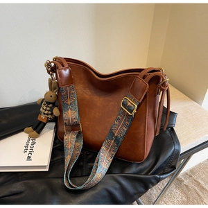 Detail of vintage brown bucket bag with artistic woven strap and cute bunny charm