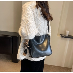 Detail of black matte leather bucket bag featuring a cute rabbit charm and metal hardware