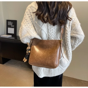 Brown bucket bag detail with woven strap design and cute bunny charm accessory