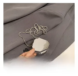 Close-up of a silver hexagonal mini chain bag with polished metal finish and snake chain