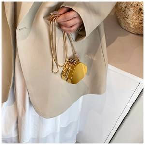 Detail of a mini golden hexagonal evening bag with a bee clasp and snake chain strap